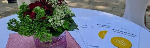 Blumen und Flyer auf einem Stehtisch