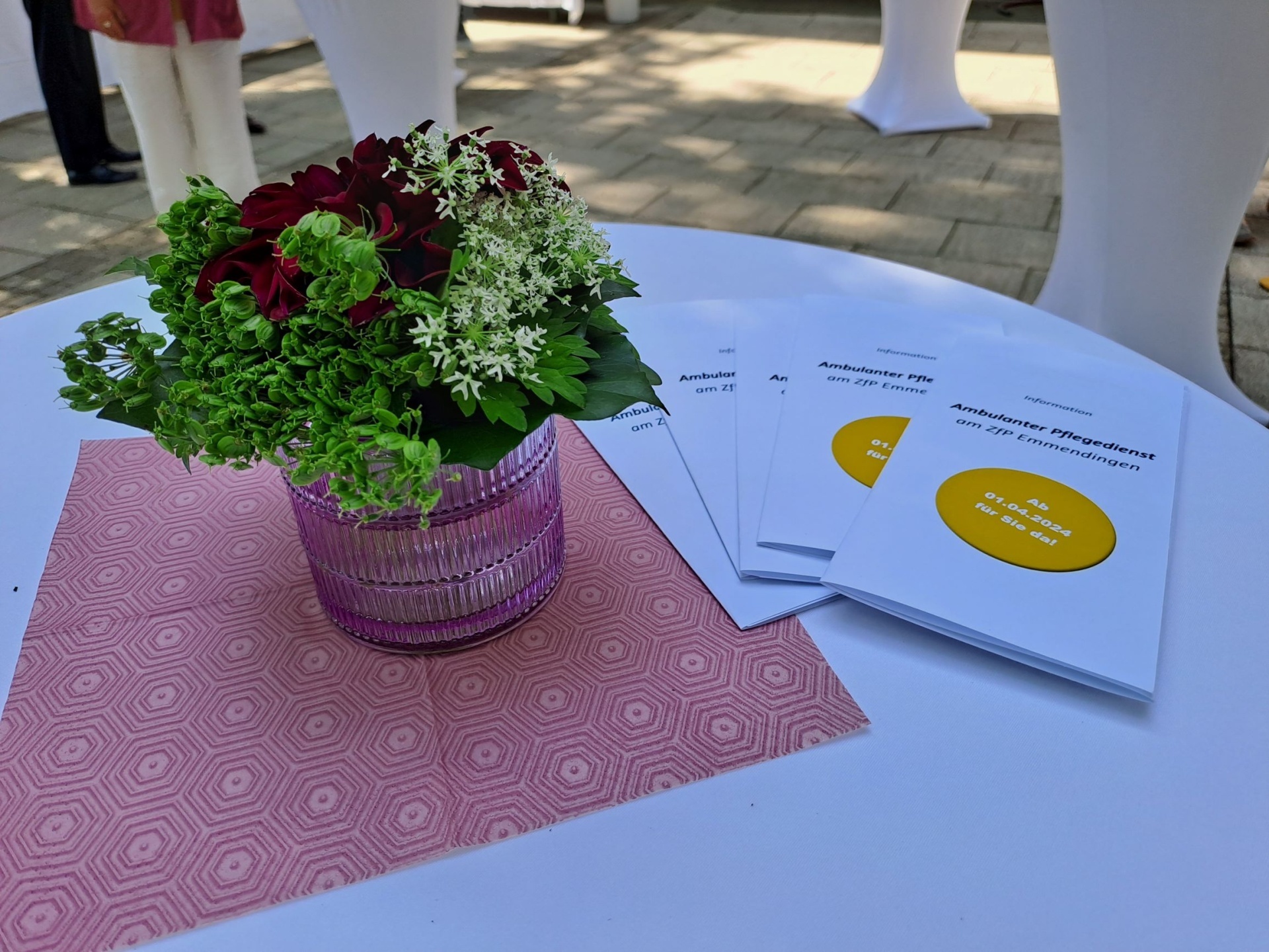 Blumen und Flyer auf einem Stehtisch