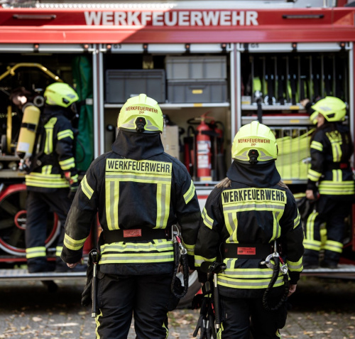 Mitarbeitende der Werkfeuerwehr vor einem Feuerwehrauto
