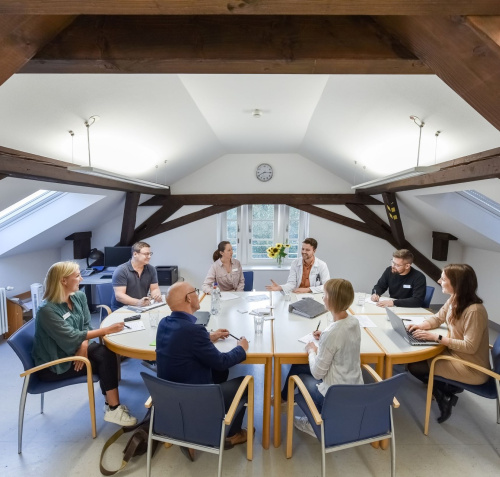 Gruppenbesprechungssituation an einem großen runden Tisch