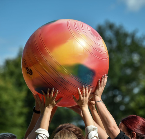 Mehrere Personen strecken gemeinsam einen bunten Gymnastikball in die Höhe